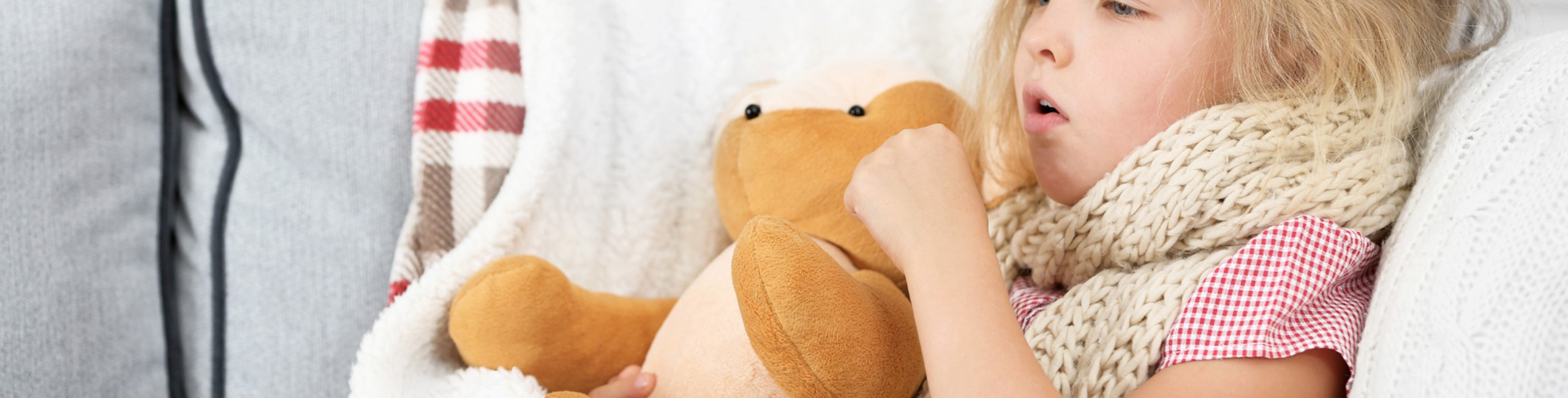 Bolesna devojčica se drži za plišanu igračku.