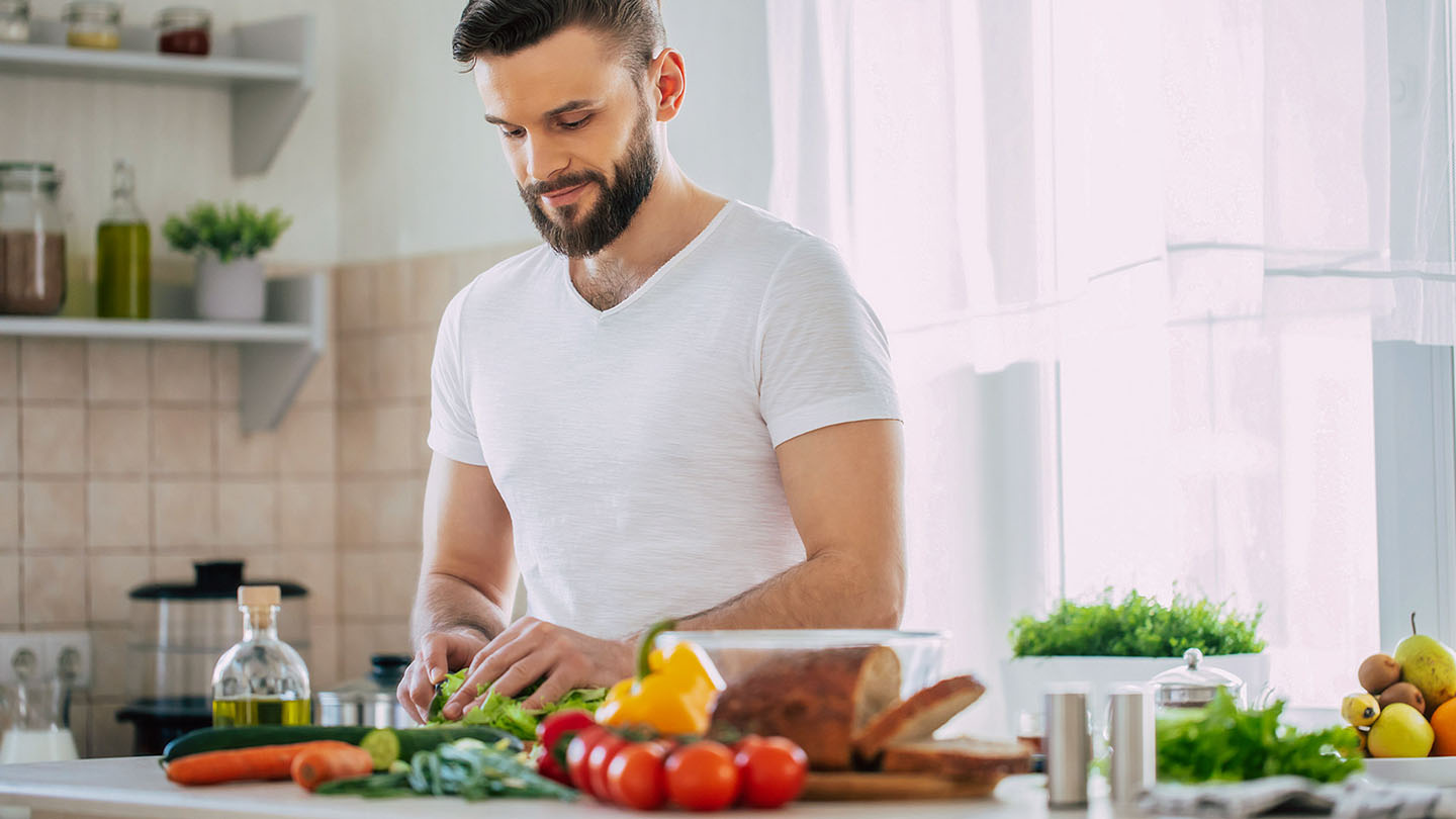 Muški sportista priprema zdrav obrok u kuhinji.